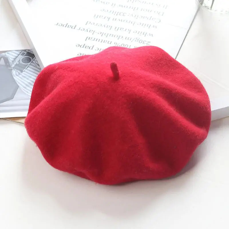 Red beret on a white surface with a magazine in the background