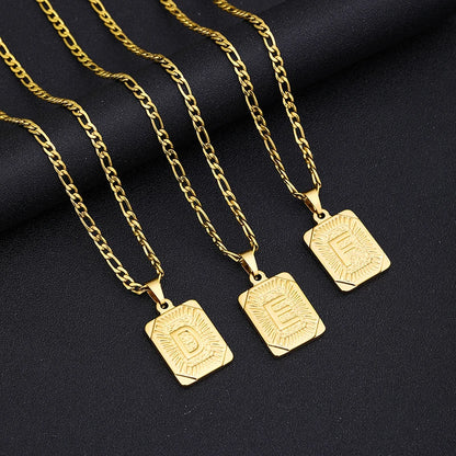 Three gold necklaces with square pendants on a black fabric background