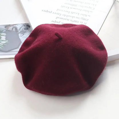 Wine red beret on a white surface with a magazine in the background
