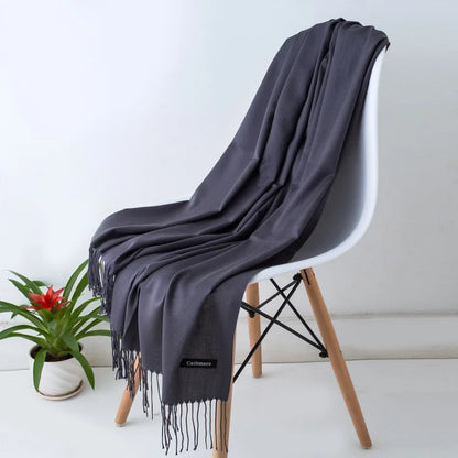 Grey scarf draped over a white chair with a plant in the background