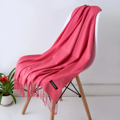 Pink throw blanket draped over a white chair with a plant in the background