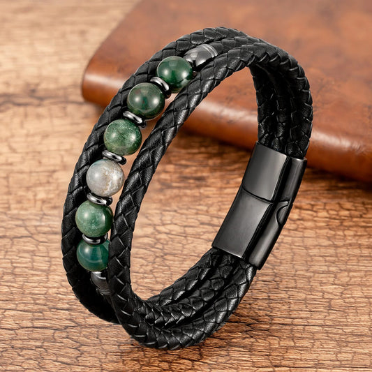 Black braided leather bracelet with green and white beads on a wooden surface
