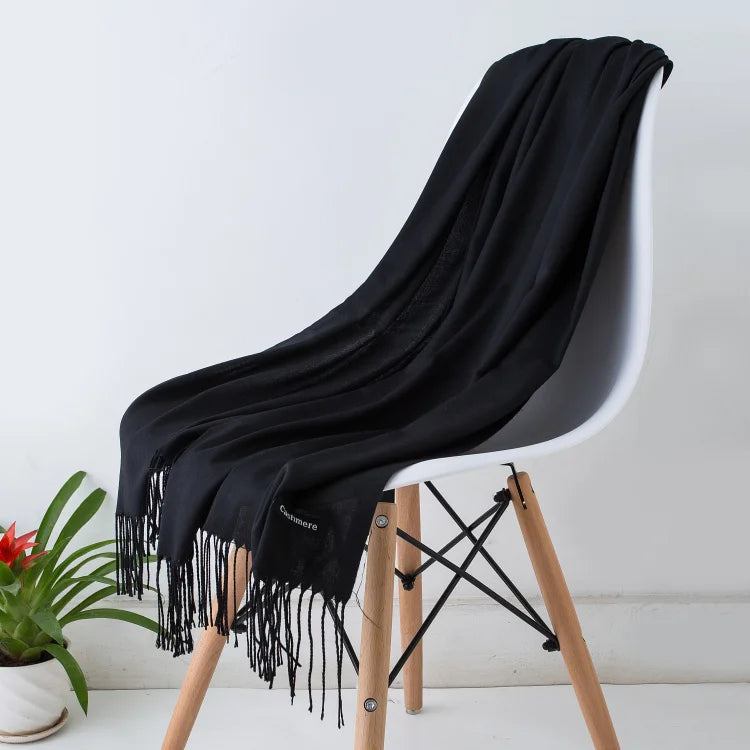 Black scarf draped over a white chair with wooden legs on a light background