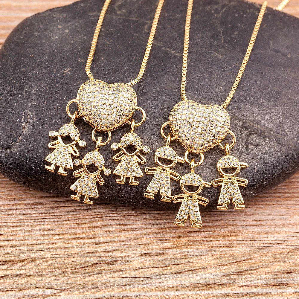 Gold necklaces with heart and figure pendants on a stone surface
