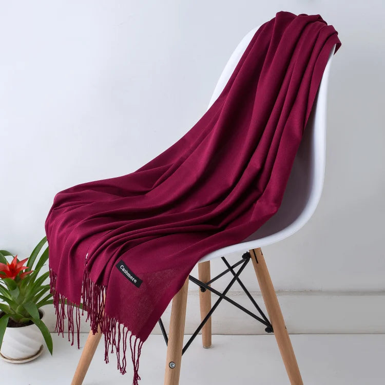 Wine red colour scarf draped over a white chair with a plant in the background