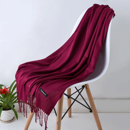 Wine red colour scarf draped over a white chair with a plant in the background