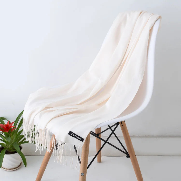 Beige scarf draped over a white chair with a plant in the background