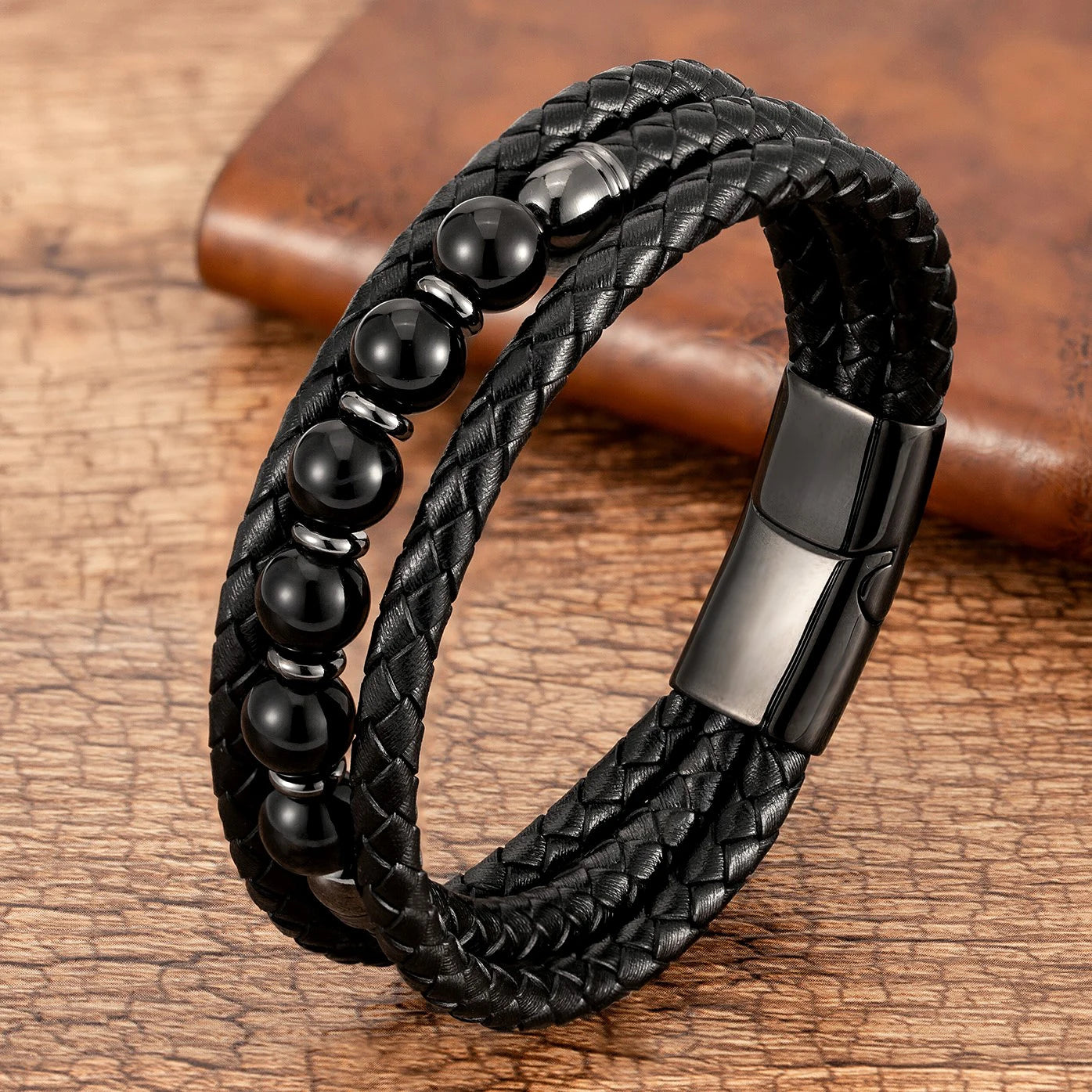 Black braided leather bracelet with beads on a wooden surface