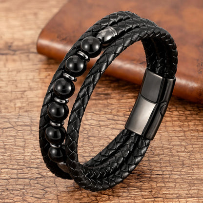 Black braided leather bracelet with beads on a wooden surface