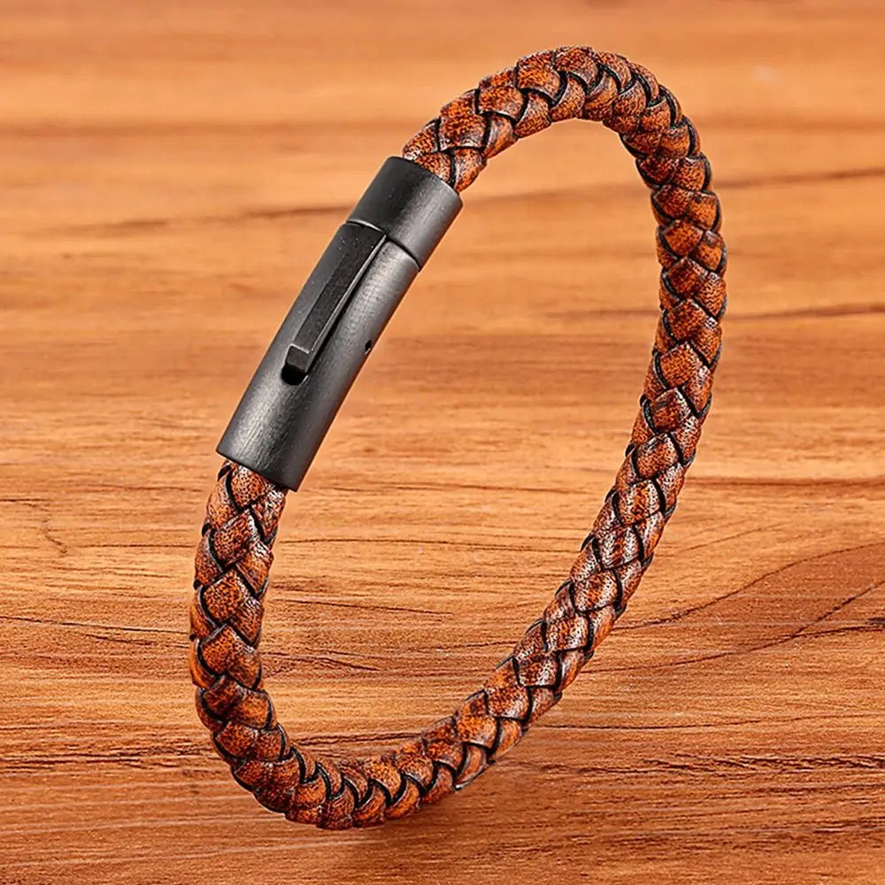 Brown braided leather bracelet with black clasp on a wooden surface