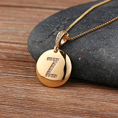 Gold necklace with a pendant featuring the letter 'Z' on a stone surface