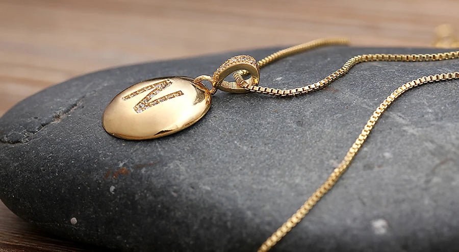 Gold necklace with a pendant on a dark stone surface