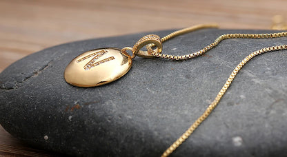 Gold necklace with a pendant on a dark stone surface
