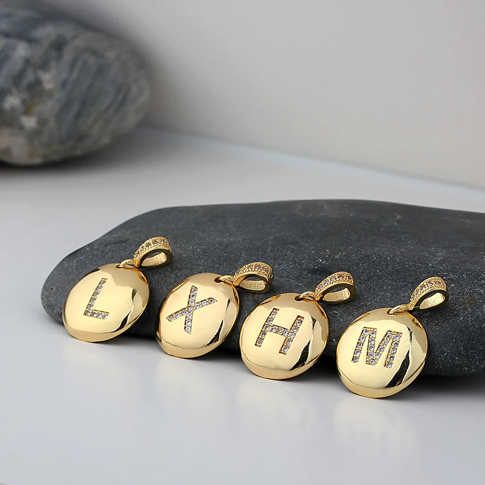 Gold pendants with initial letter on a stone surface