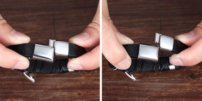 Black leather strap with silver buckles held by a hand on a wooden surface.