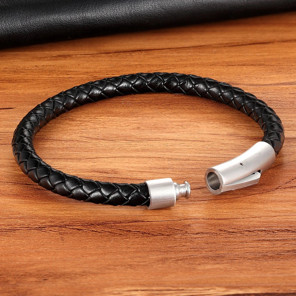 Black braided leather bracelet with silver clasp on a wooden surface
