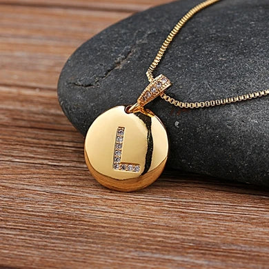 Gold necklace with a round pendant on a stone surface