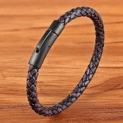 Grey braided leather bracelet with a black clasp on a wooden surface