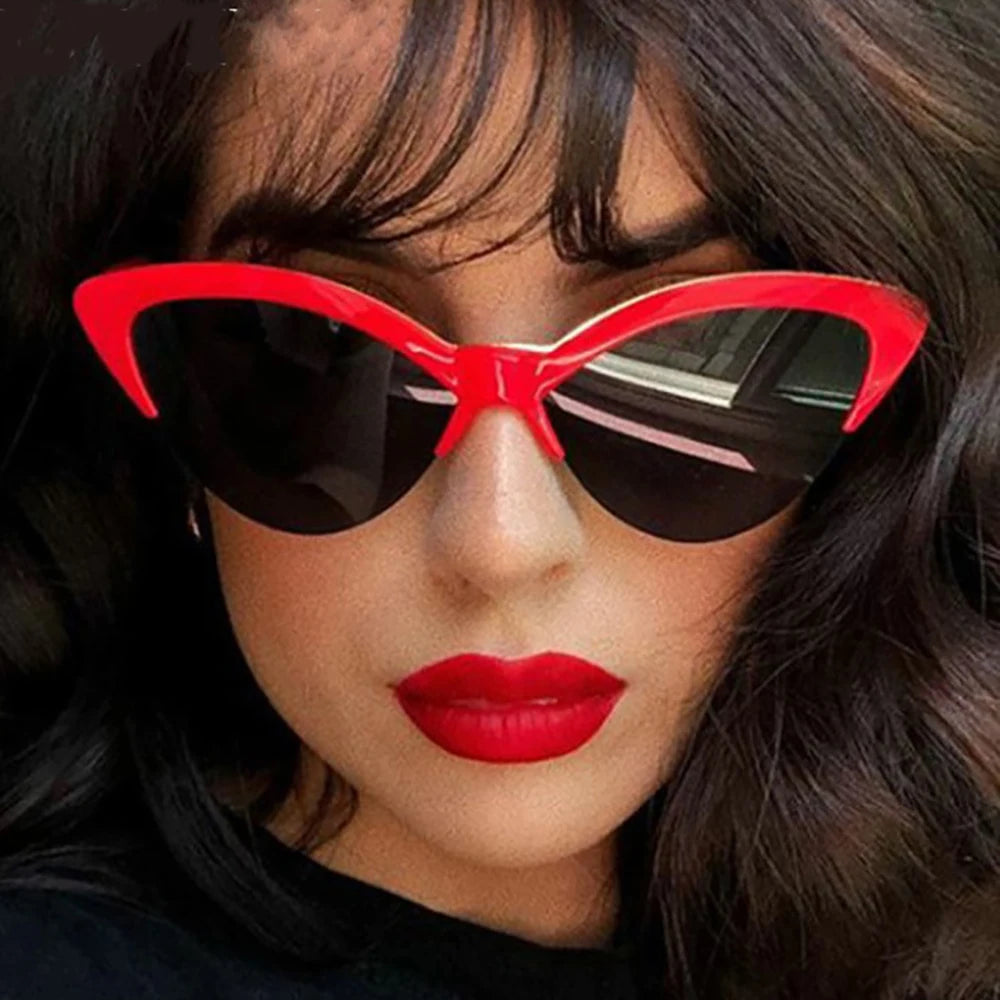 Person wearing red cat-eye sunglasses with a dark background