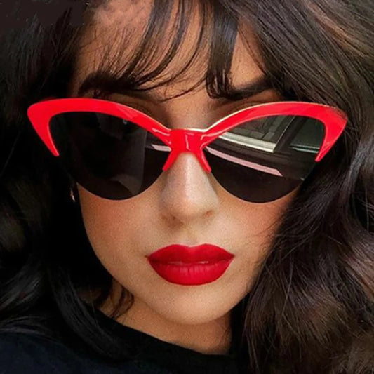 Person wearing red cat-eye sunglasses with a dark background