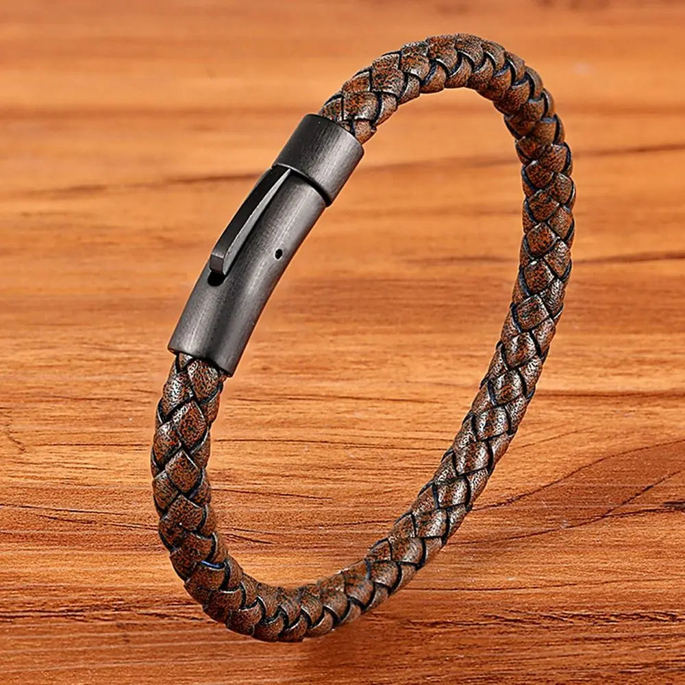 Brown braided leather bracelet with a metallic clasp on a wooden surface