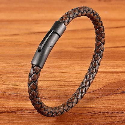 Brown braided leather bracelet with a metallic clasp on a wooden surface