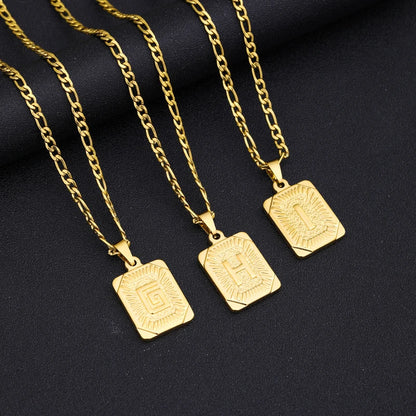 Three gold necklaces with square pendants on a black background