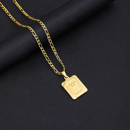 Gold necklace with a square pendant on a black fabric background