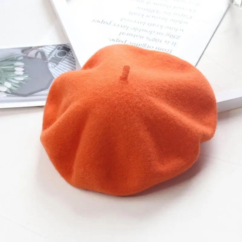 Orange beret on a white surface with a magazine in the background