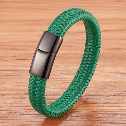 Green braided bracelet with a black metallic clasp on a wooden surface
