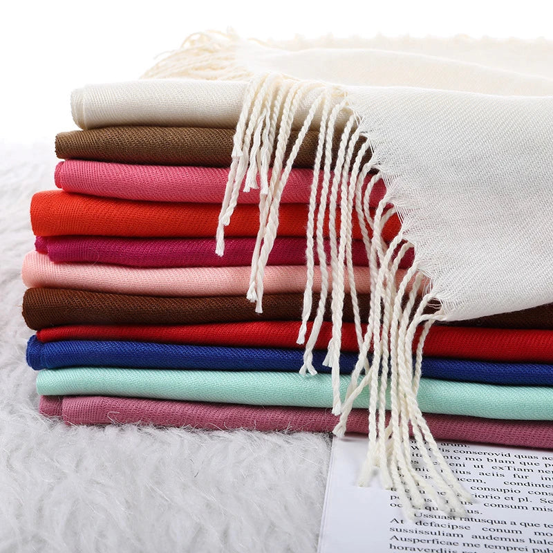 Stack of colourful scarves with tassels on a white surface