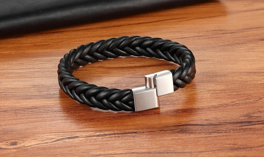 Black braided bracelet with a silver clasp on a wooden surface