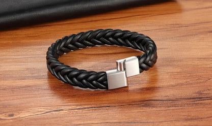 Black braided bracelet with a silver clasp on a wooden surface