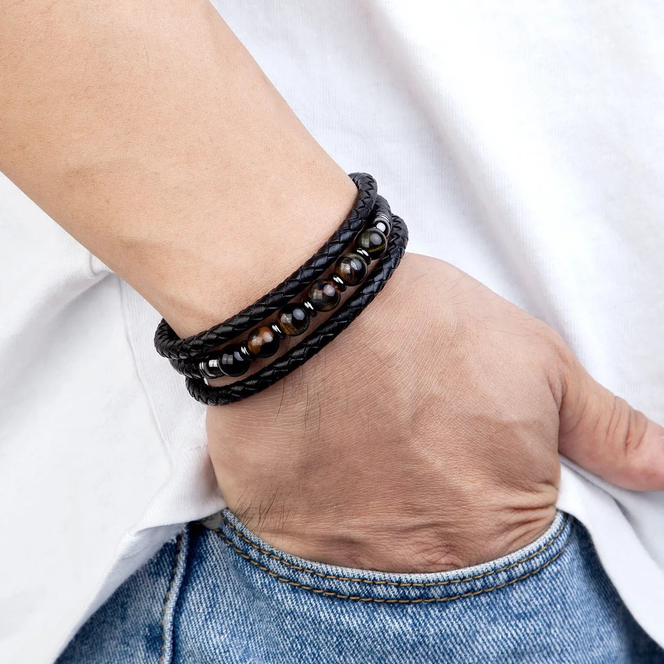 Hand wearing a black beaded bracelet on a white background