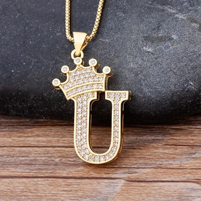Gold necklace with a letter 'U' pendant on a dark surface