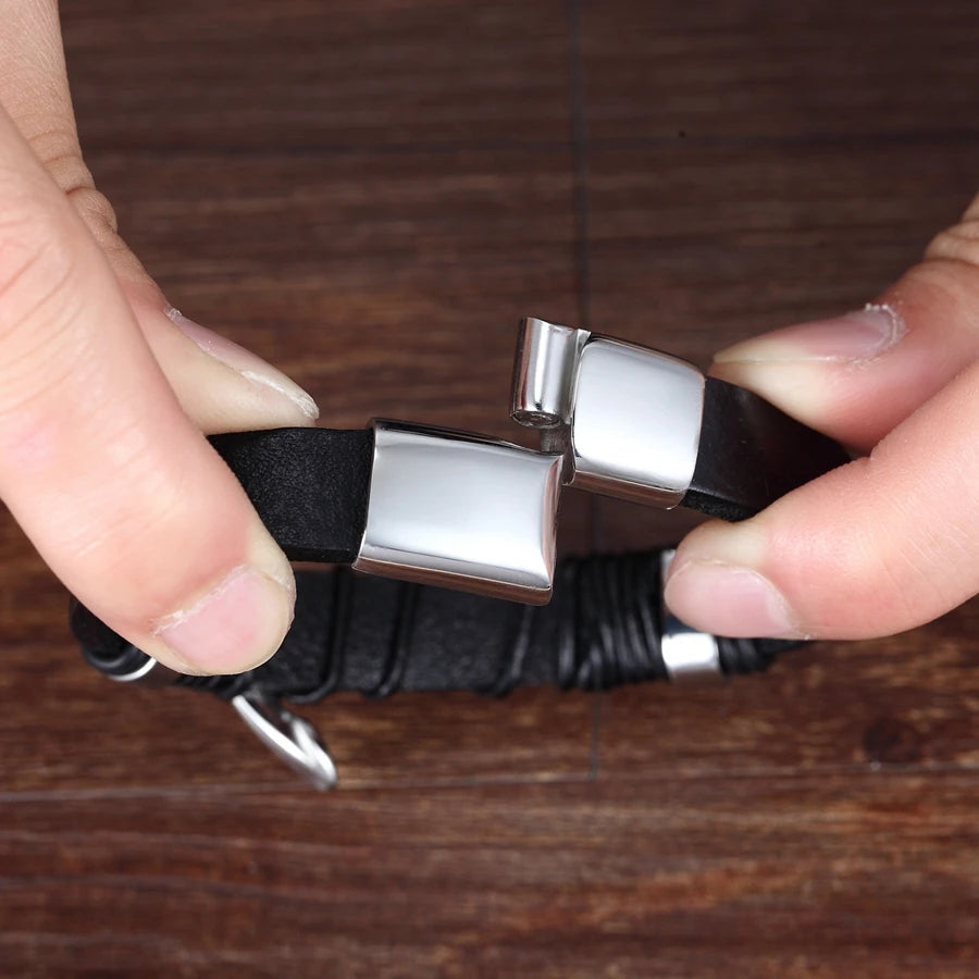 Black bracelet with silver clasp held by a hand on a wooden surface