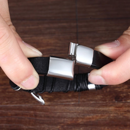 Black bracelet with silver clasp held by a hand on a wooden surface