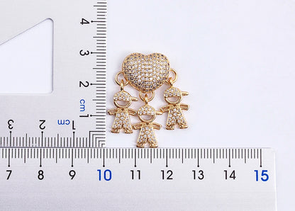 Gold charm with children and a heart shape next to a ruler for scale on a white background