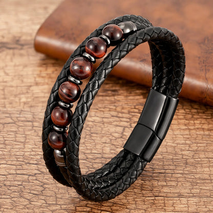 Black braided leather bracelet with red beads on a wooden surface