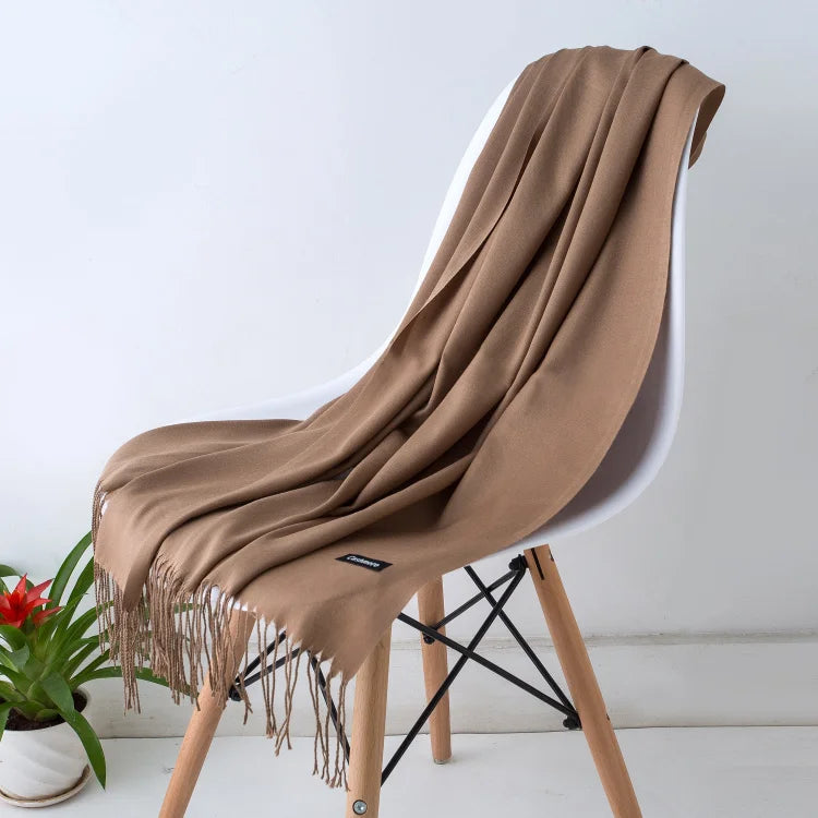 Brown scarf draped over a white chair with a plant in the background