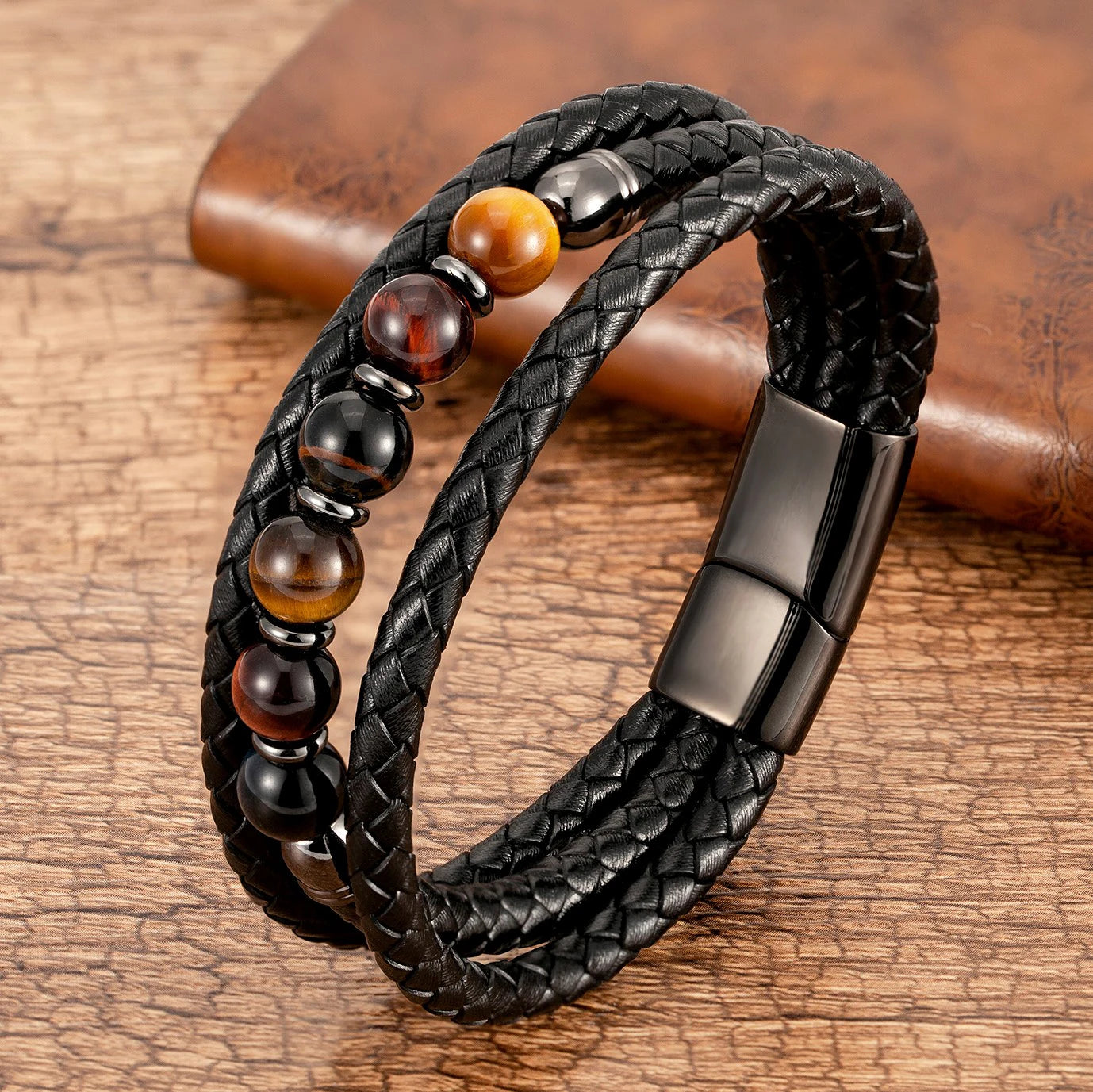 Black braided leather bracelet with beads on a wooden surface