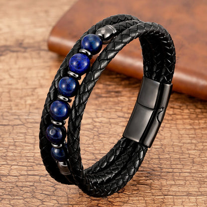 Black braided leather bracelet with blue beads and a magnetic clasp on a wooden surface