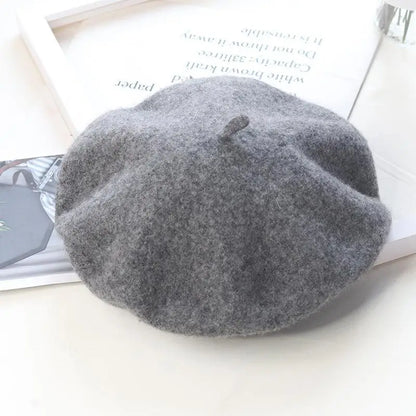 Grey beret on a white surface with a magazine underneath