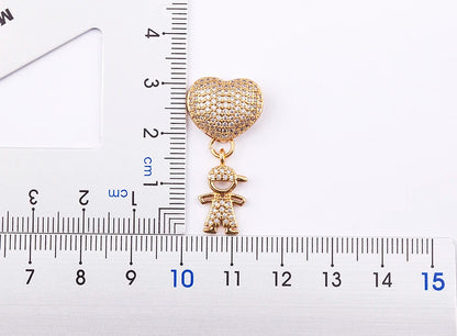 Gold heart-shaped charm with a child figure on a white background with a ruler for scale.
