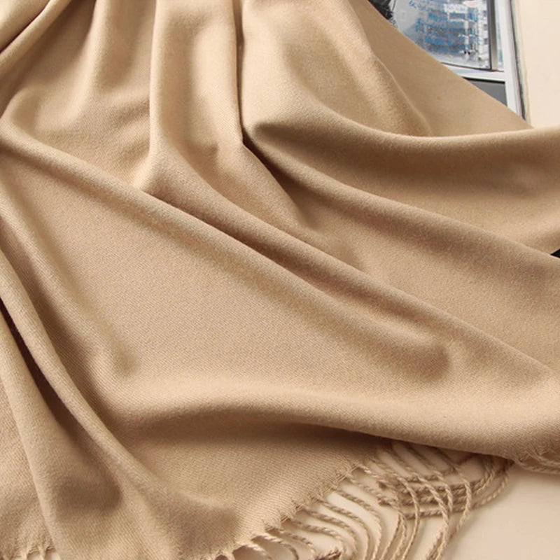 Beige scarf with fringe details on a plain background
