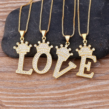 Gold necklaces with 'LOVE' pendants on a stone and wood background