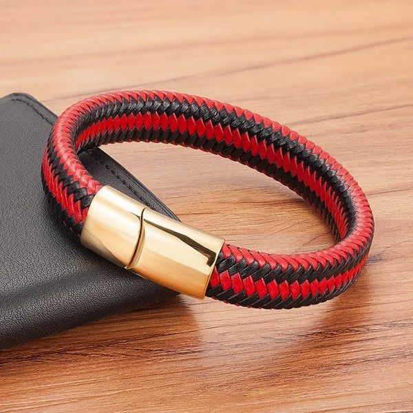 Red and black braided bracelet with a gold clasp on a wooden surface