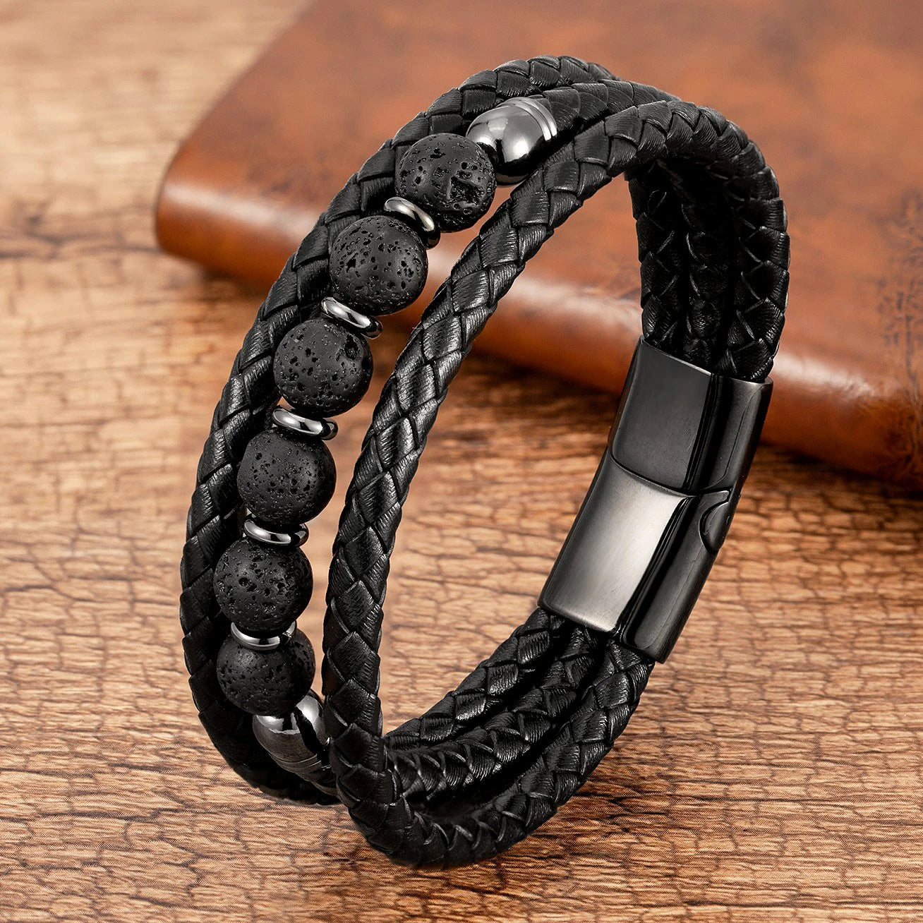Black braided leather bracelet with black beads on a wooden surface