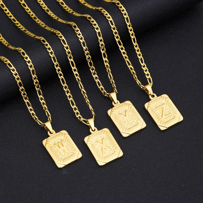 Gold necklaces with square pendants displaying letters on a black background