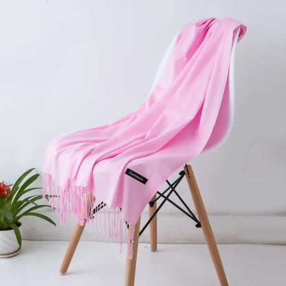 Pink scarf with tassels draped over a chair against a white background